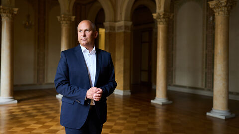 Justizminister Poseck steht in einem Saal mit vielen Säulen an den Wänden.