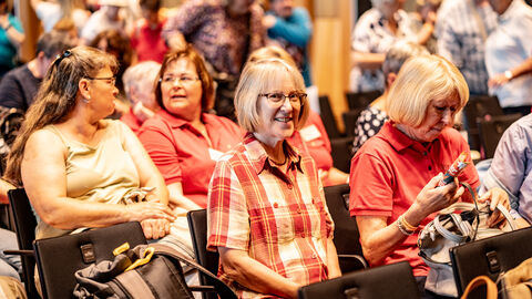 Mehrere Personen sitze in einer Reihe und lachen.
