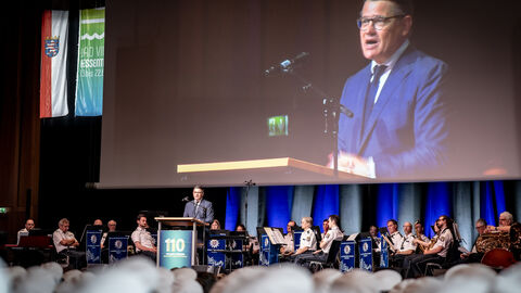 Ministerpräsident Boris Rhein steht auf einer Bühne vor vielen Menschen in Uniform.