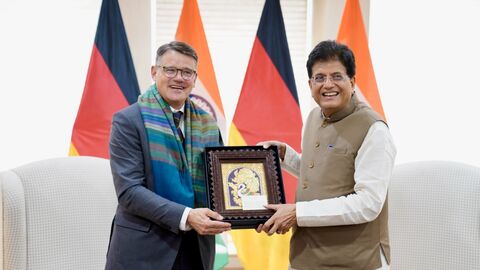 Ministerpräsident Rhein und indischer Minister für Handel und Industrie, Piyush Goyal, halten einen Rahmen hoch.