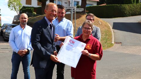 Hessens Chef der Staatskanzlei, Axel Wintermeyer, übergibt die Urkunde „Starkes Dorf“ an Linda Kimmel vom Heimatverein Untergeis. 